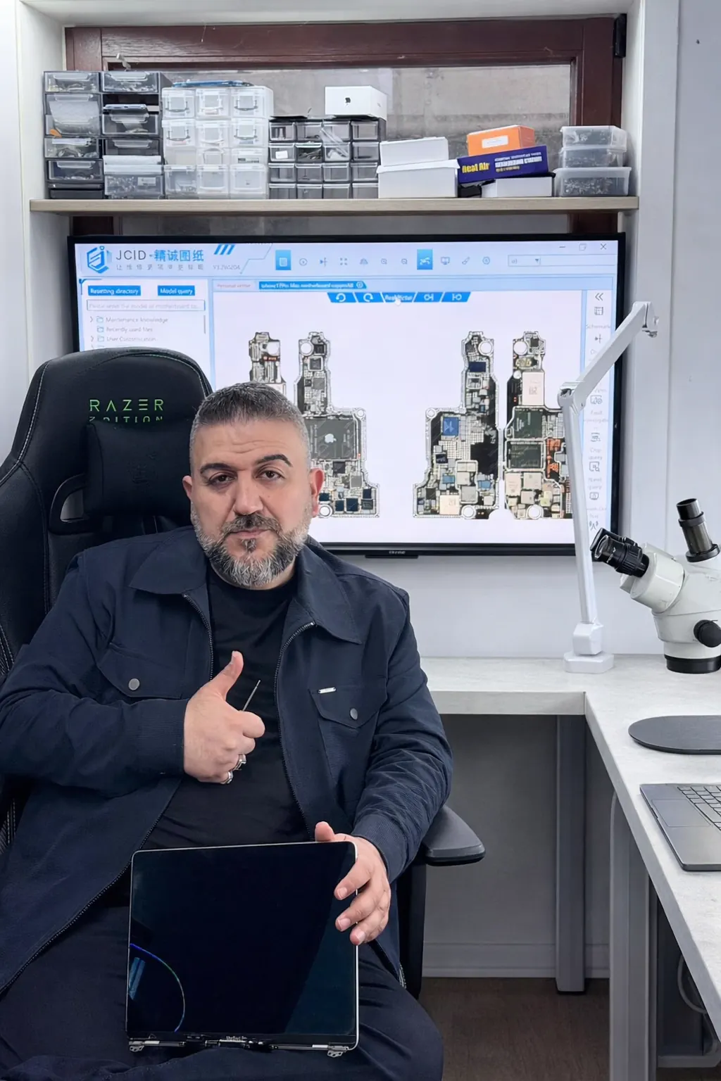 Expertoo-Techniker mit einem MacBook-Display vor Platinen-Schaltplänen